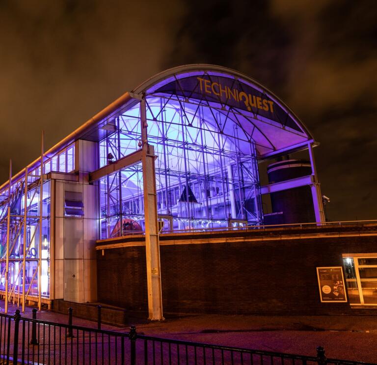 An exterior shot of Techniquest lit up at night.