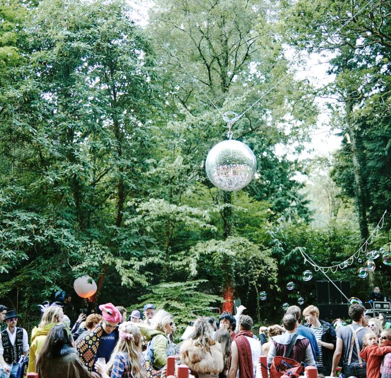 People dancing in the woods at a festival.