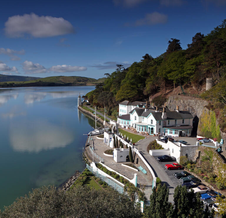 An aerial view of a hotel on the edge of an estuary with mountains beyond.