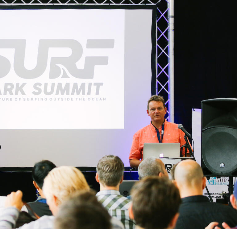 A speaker on stage at the Surf Park Summit.