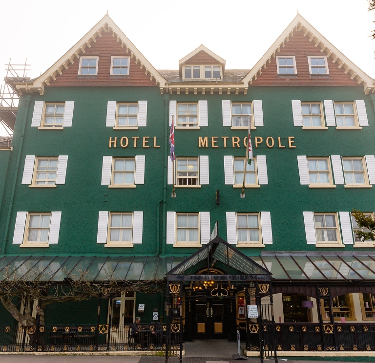 Front view of a large, green painted hotel.