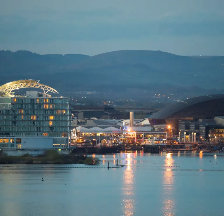 View of Cardiff Bay at dusk with lights reflecting in the water.