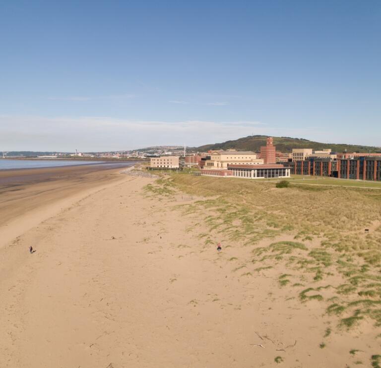 Swansea University buildings with sea and sand.