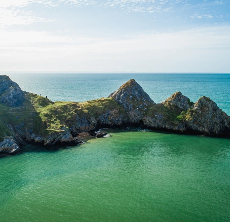 Three cliffs with water and blue sky.