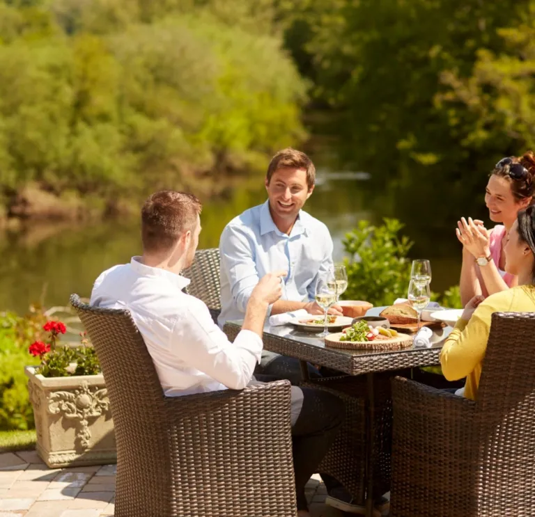 A group of people dining alfresco near a lakeside. 