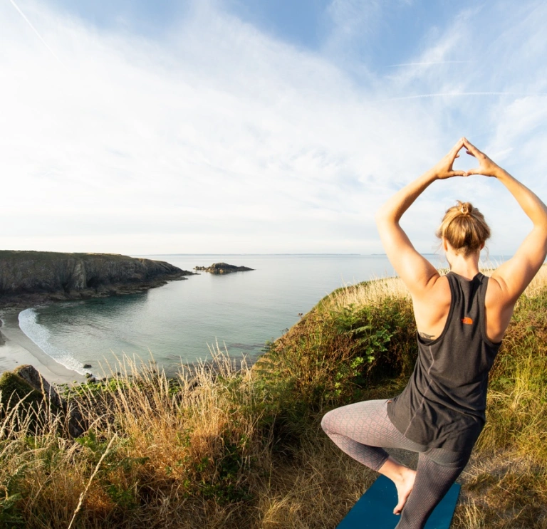 Person doing yoga overlooking beach.