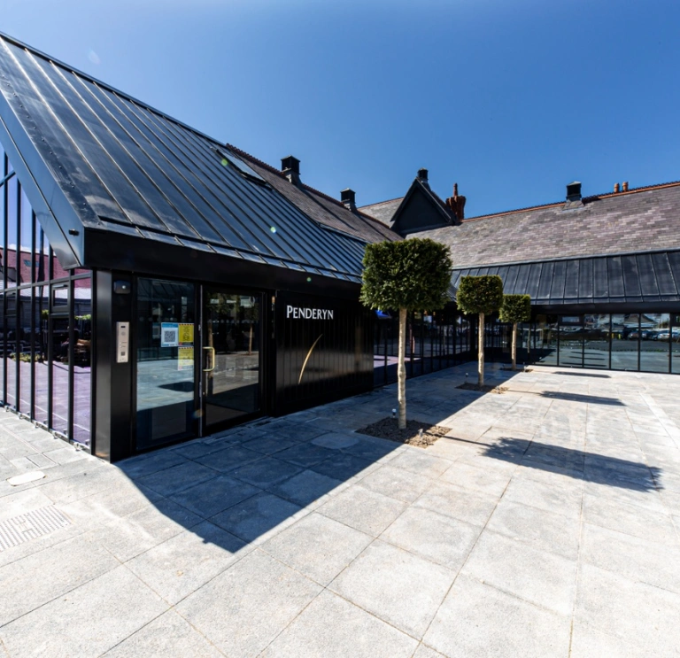 Outside Penderyn Distillery Llandundo, glass building and blue sky.