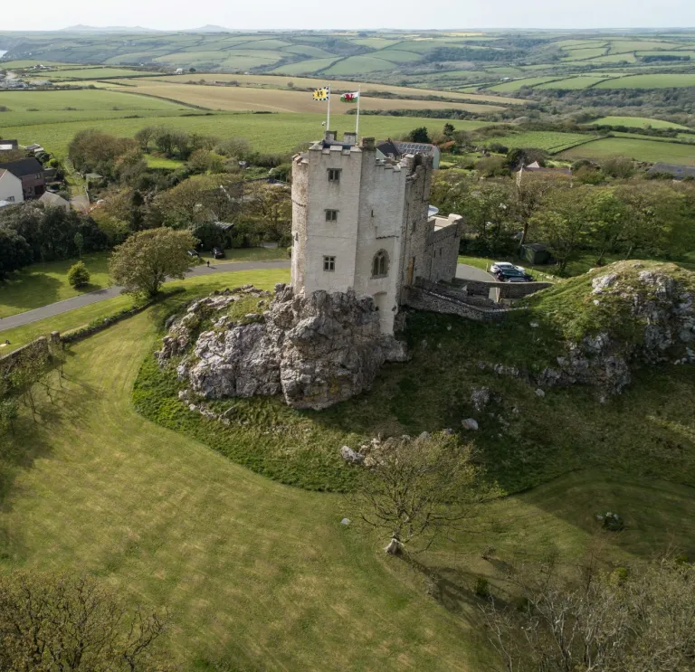 A castle hotel on a hill with the coastline beyond.