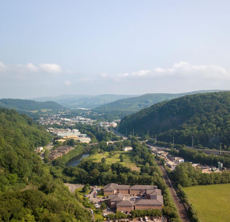 Aerial view of a major road through the valleys with a castle perched on a mountain.