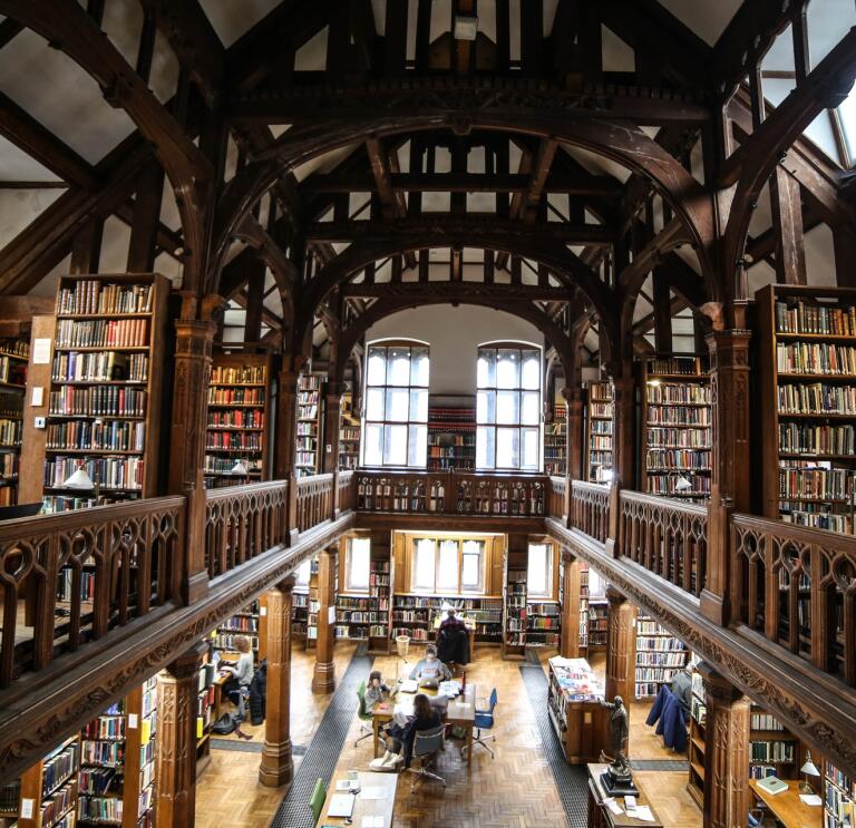 People in a library full of books on upper and lower levels