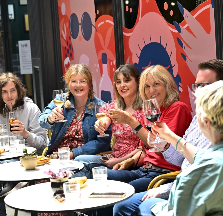 Group of people sitting at dining tables eating and drinking on a food tour.
