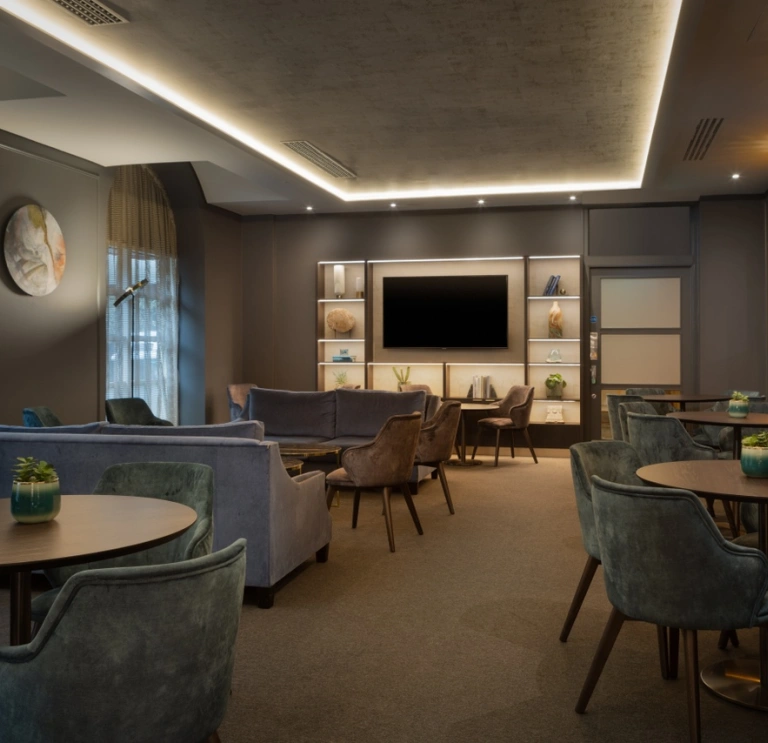 Hilton Cardiff executive lounge features soft blue chairs and wooden tables