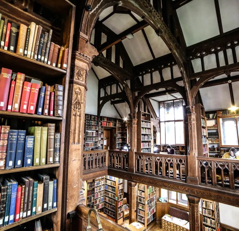 books on shelves floor to ceiling with wooden beams around ceiling