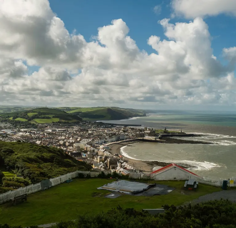 view of Aberystwyth coat with white clouds blue sky and mountains in teh background