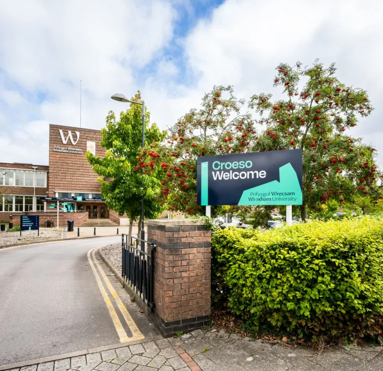 exterior of Wrexham University entrance with croeso welcome sign on hedge