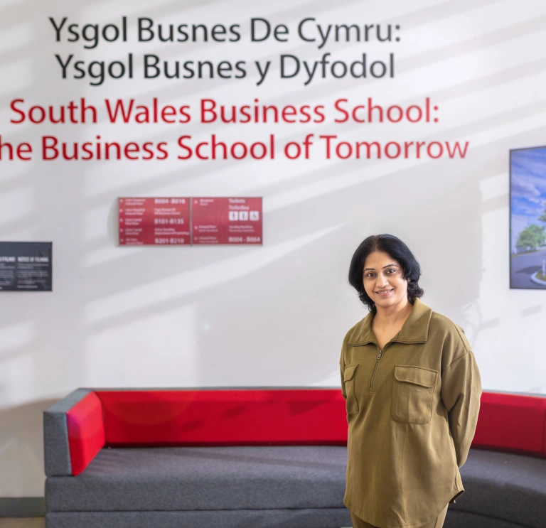 Interior of South Wales Business School with a person standing in front of wall signage
