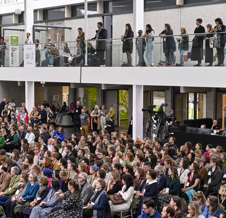 people seated and standing on upper and lower floors of the museum during the conference 