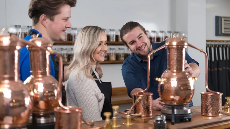 A man showing a couple around a distillery.