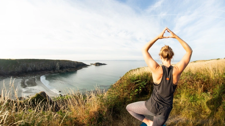 Person doing yoga overlooking beach.