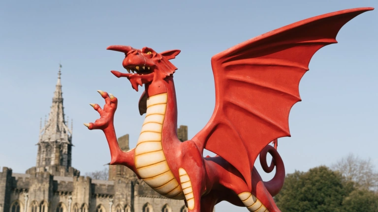 A statue of a Welsh dragon with a castle in the background.