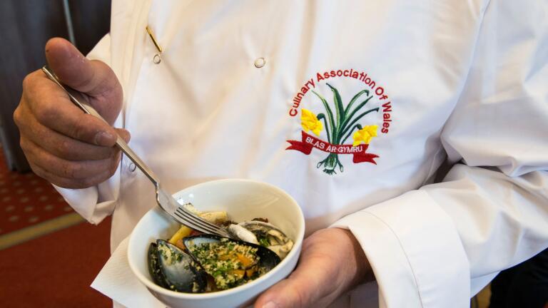 Chef in apron displaying Culinary Association of Wales badge 