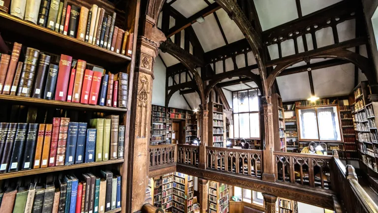 books on shelves floor to ceiling with wooden beams around ceiling