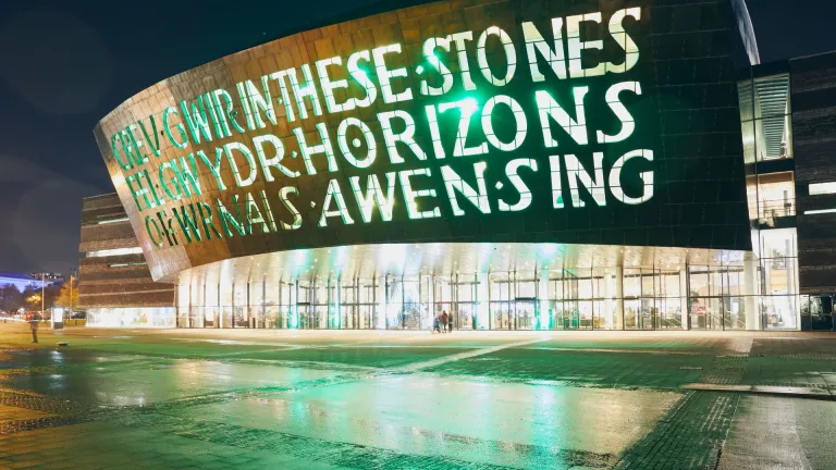outsideof the wales millennium centre at night with words written into the building lit up