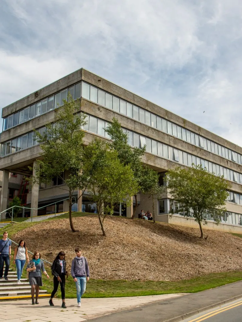 External view of a university building with students walking down the steps.