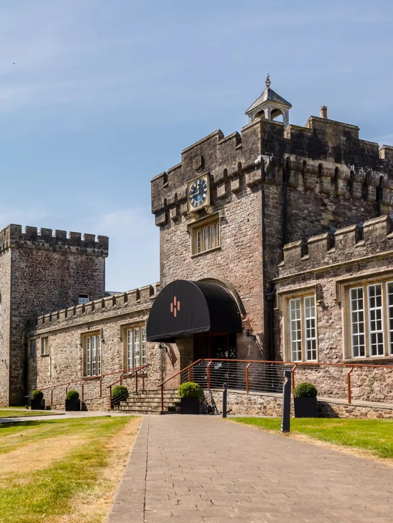 A path leading to a castle distillery with a large tree next to it.