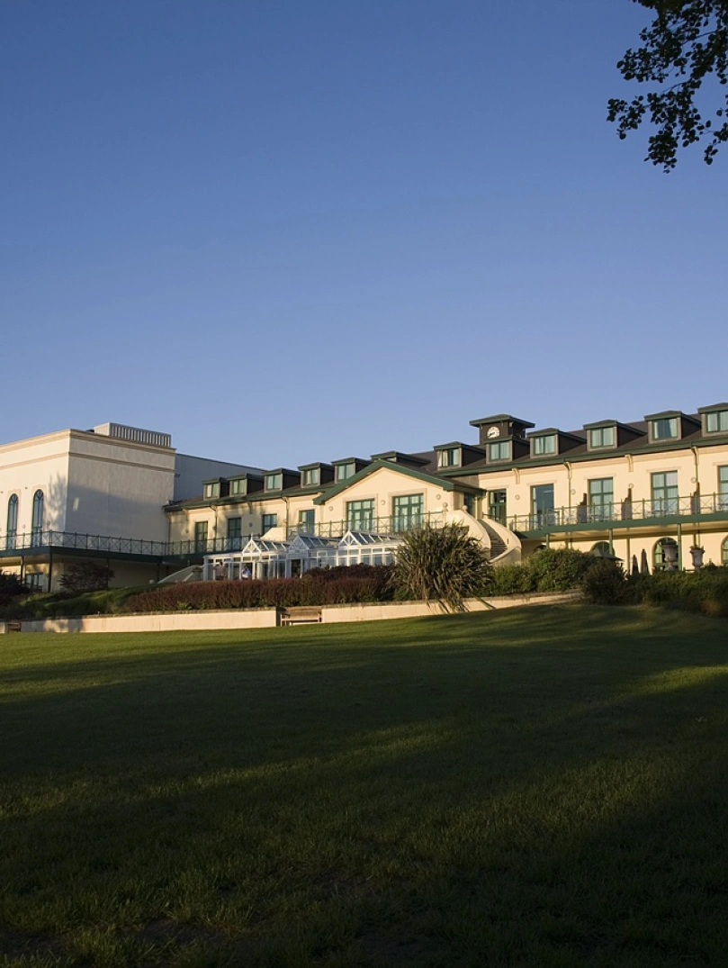 The frontage of a large hotel with lawns in the foreground.