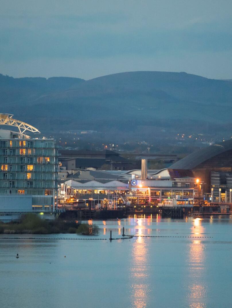 View of Cardiff Bay at dusk with lights reflecting in the water.