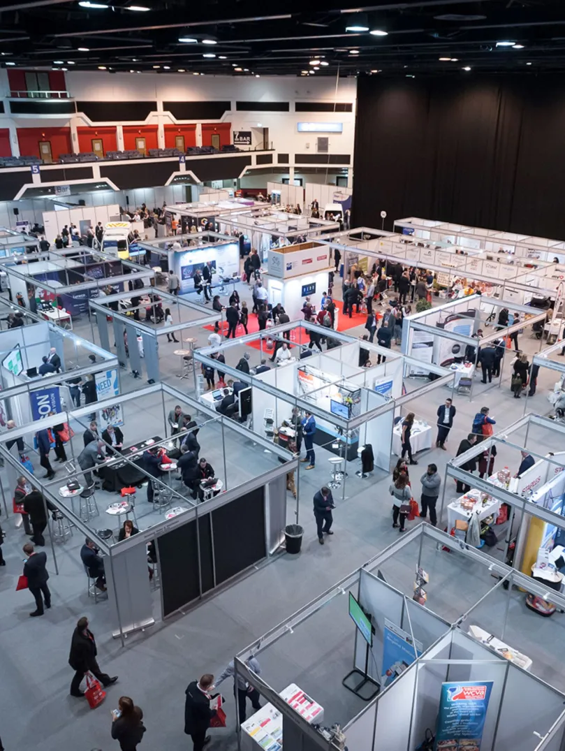 Exhibition space with shell scheme stands and people walking around.