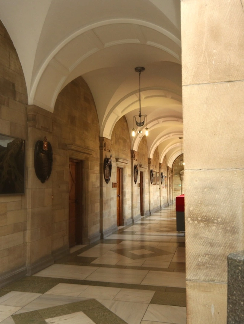 Aspects of Main Arts Building Bangor University with stone walls tiled cream floor and head statue of man in the forefront.