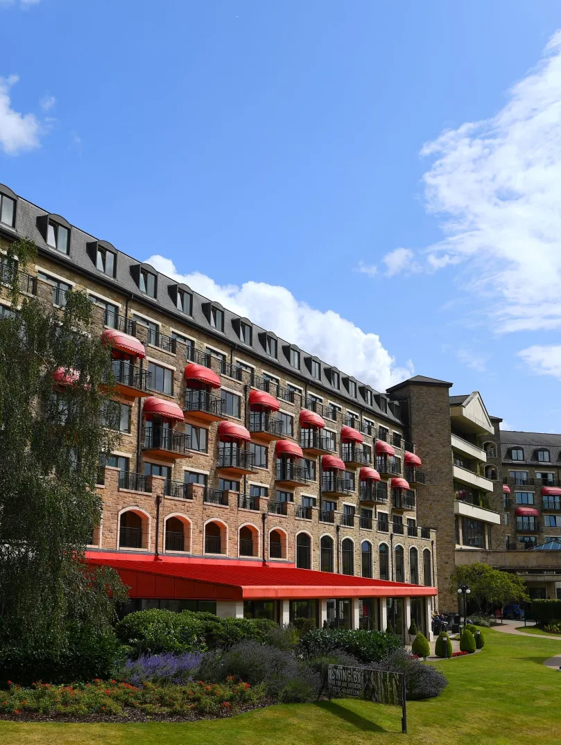 Exterior of hotel with manicured green lawns and trees.