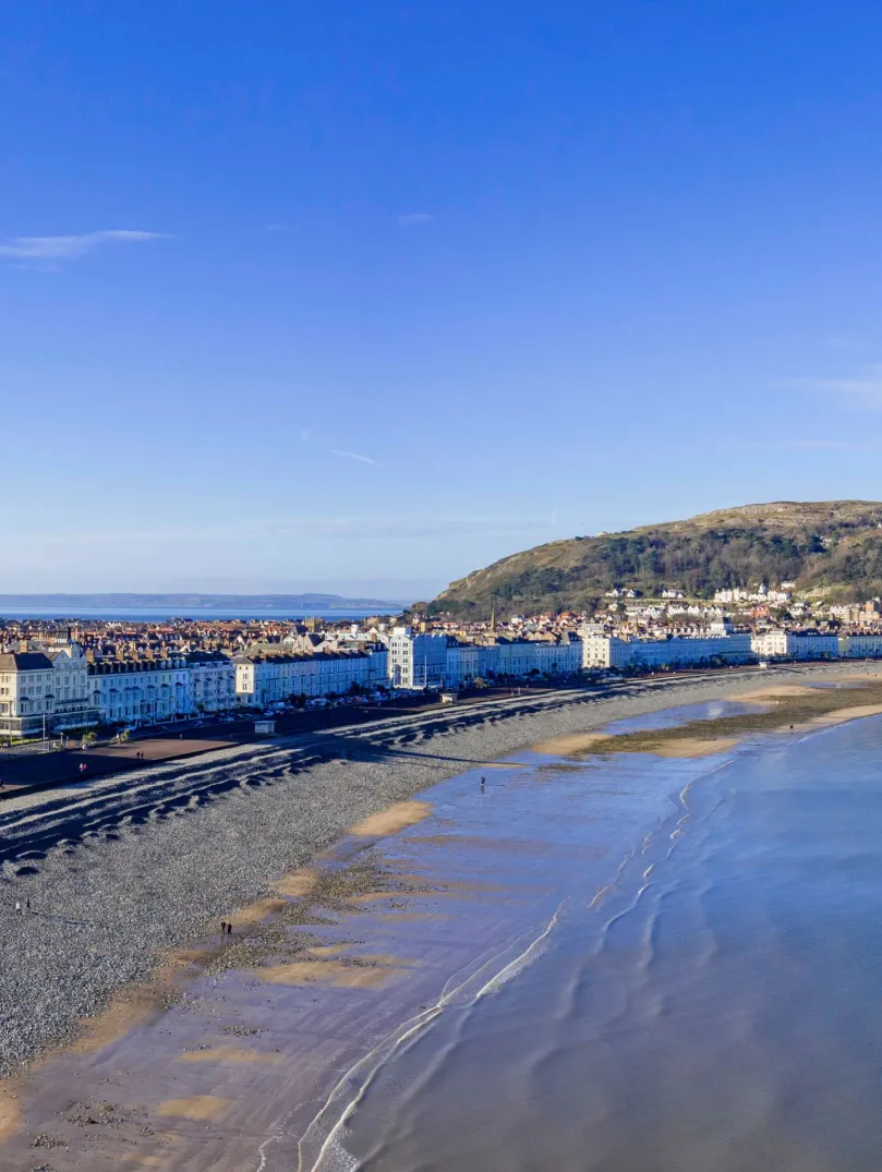 The shoreline of a beach resort lined with hotels with cliff tops beyond.
