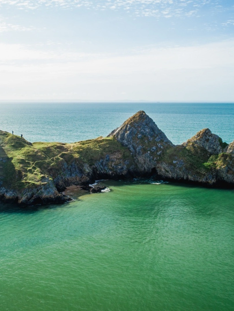 Three cliffs with water and blue sky.