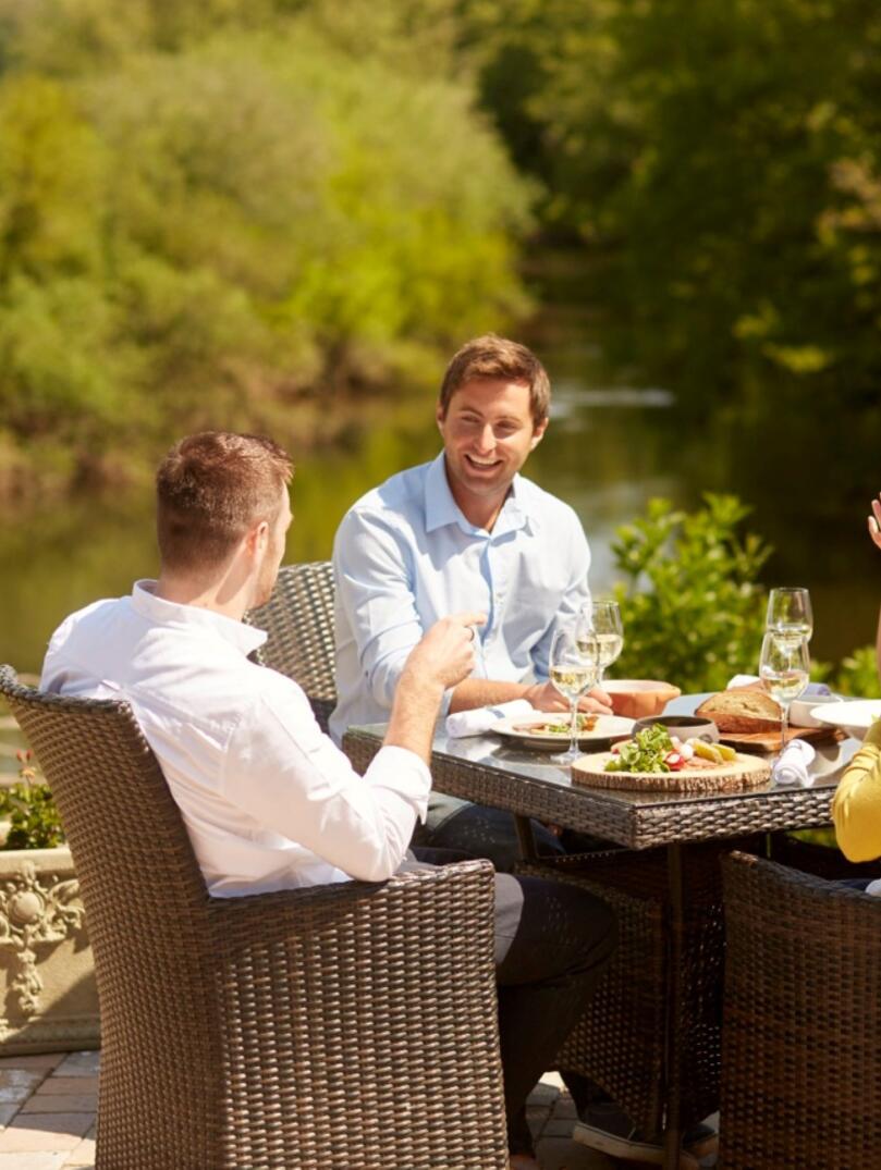 A group of people dining alfresco near a lakeside. 