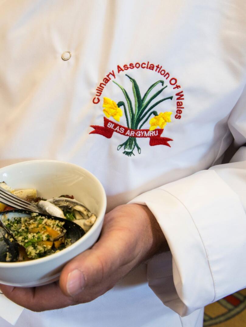Chef in apron displaying Culinary Association of Wales badge 