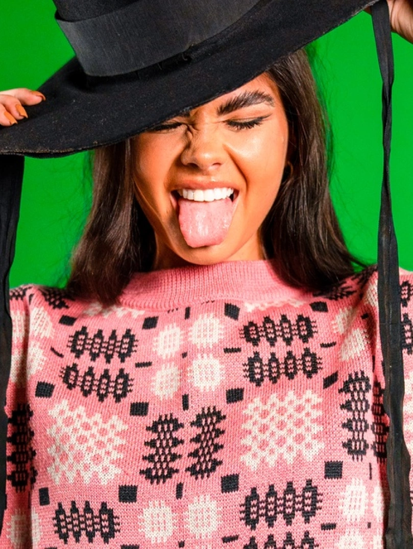 Woman in Welsh hat with her tongue out in Welsh fabric jumper 