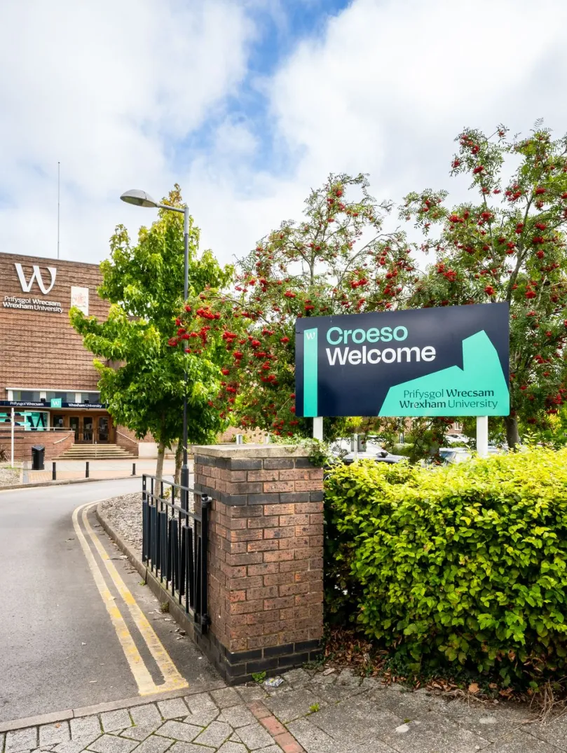 exterior of Wrexham University entrance with croeso welcome sign on hedge