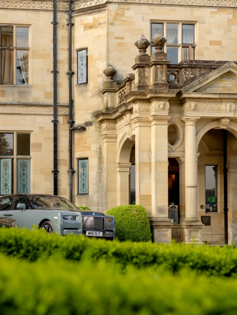 Grand stone country house entrance with classical columns and parked luxury cars Provide your feedback on BizChat