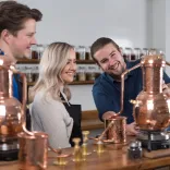 A man showing a couple around a distillery.