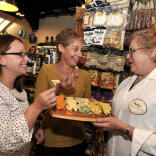 A couple of ladies tasting cheese in a delicatessen on a food tour.