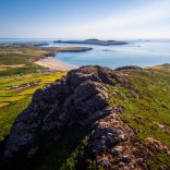 View from a headland of a beach and coastline on a sunny day.
