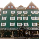 Front view of a large, green painted hotel.