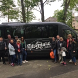 Group of people standing outside mini bus.
