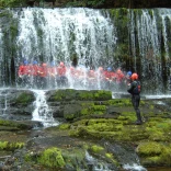 Group in safety gear standing behind a waterfall.