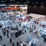 Exhibition space with shell scheme stands and people walking around.