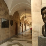 Aspects of Main Arts Building Bangor University with stone walls tiled cream floor and head statue of man in the forefront.
