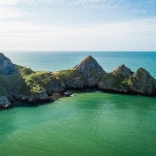 Three cliffs with water and blue sky.